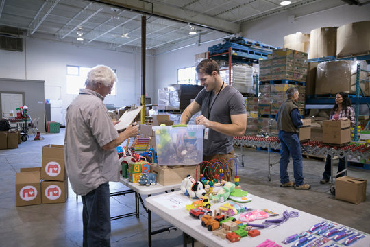 Male volunteers sorting toys for toy drive in warehouse
