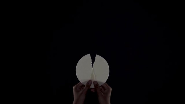Hands of priest holding a divided sacramental bread