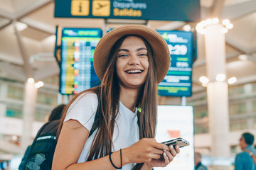 at the airport opposite the scoreboard, the girl with the phone smiles widely - 316148674