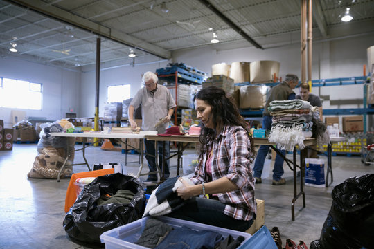 Female volunteer sorting clothing for clothing drive in warehouse