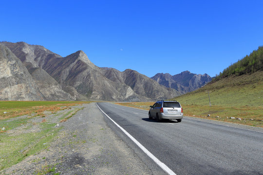 A car on the background of picturesque rocks rides in the Altai Mountains in Russia