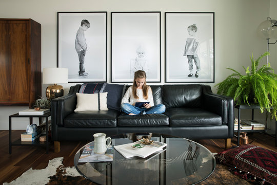 Girl using digital tablet on leather living room sofa