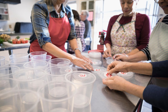 Female volunteers cooking in soup kitchen, preparing soup containers