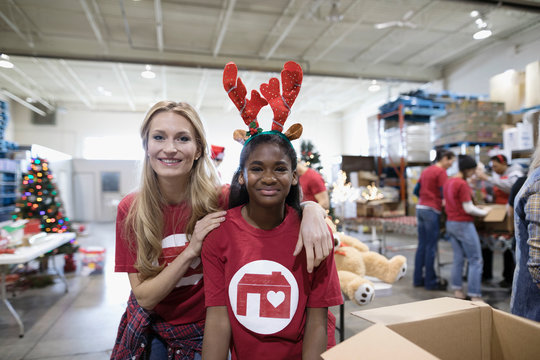 Portrait smiling female volunteers in reindeer antlers volunteering in warehouse