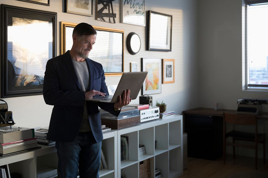 Creative mature businessman entrepreneur working at laptop in studio office