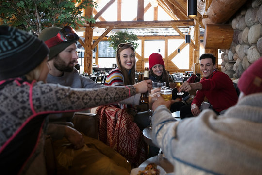 Friends Enjoying Apres-ski, Toasting Beers In Ski Resort Lodge