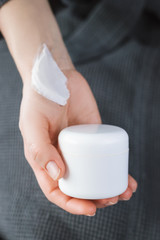 Fototapeta na wymiar Background with blank white cream bottle tube in a female hands. Branding mock-up. Vertical photo.
