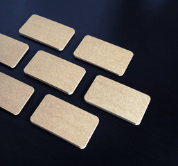 Blank brown paper business cards on black wood table background. Copy space for text.