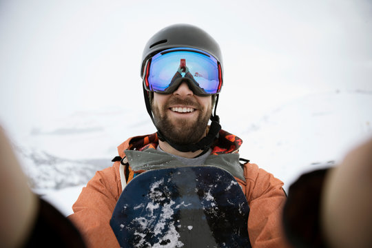 Selfie portrait smiling, confident male snowboarder
