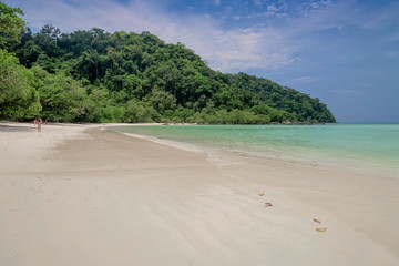 view of white sand beach with green forest and blue-green sea with blue sky background, Mai Ngam Beach, Surin island, Mu Ko Surin National Park, Phang Nga, southern of Thailand.