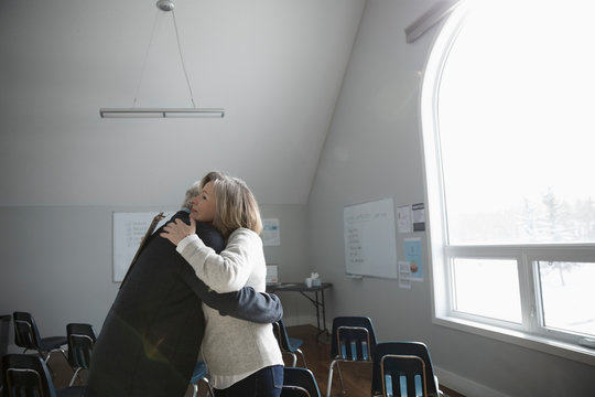 Senior friends hugging at support group in community center