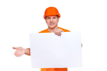 White smiling middle-aged handsome worker wearing orange hard hat, holding blank paper sheet in hand