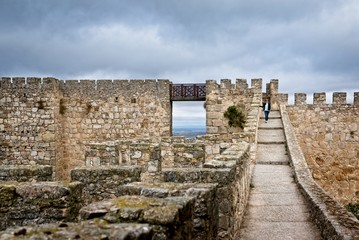A woman tourist walks on the wall of a medieval castle