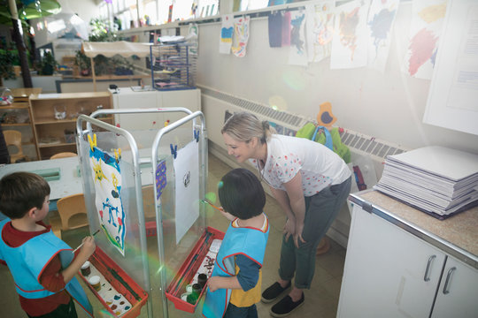 Preschool teacher and students painting in classroom