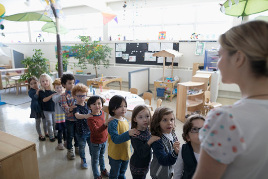 Preschool Students Lining Up For Teacher In Classroom