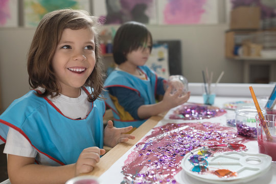 Smiling preschool girl painting in art class