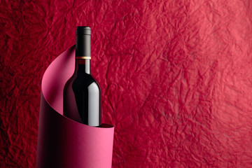 Bottle of red wine on a red background. Copy space.