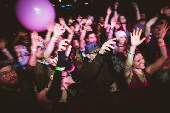 Milennials dancing, cheering at music concert in nightclub
