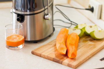 detox. smoothies. the process of making juice in the kitchen. A glass of fresh carrot juice. carrot...