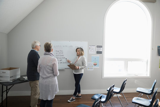 Woman At Whiteboard Leading Grief Counseling Support Group In Community Center