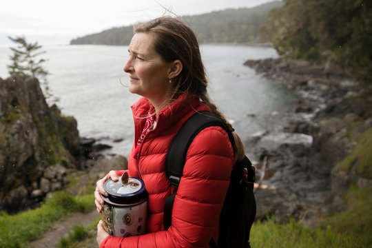 Woman with urn spreading ashes on cliff overlooking ocean