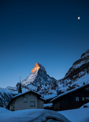 sunrise on Matterhorn with Alpenglow and moon in winter