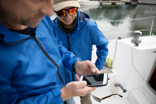 Sailing team using smart phone on sailboat