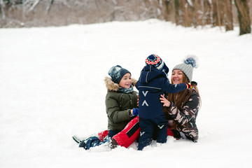 Happy christmas holidays. Pretty mother and two sons having fun together while lying on snow