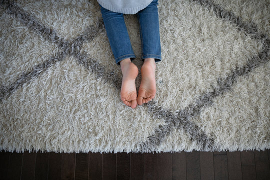 View from above girl with bare feet laying on rug