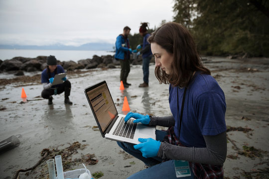 Eco-friendly female scientist with laptop on beach