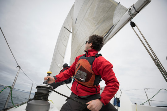 Man adjusting sail rigging on sailboat