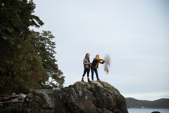 Mother and daughter spreading ashes on rocks