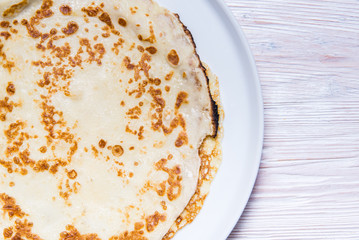 Fried pancake on porcelain dich and wooden table