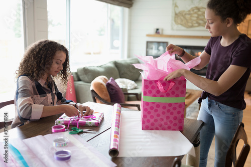 Teenage girls wrapping birthday gift
