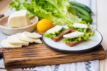 Sandwiches with green salad leaves and feta goat cheese. Healthy vegetarian snack.