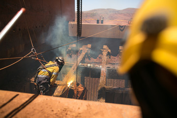 Rope access boiler maker abseiler wearing safety harness, helmet using two rope in fall arrest...