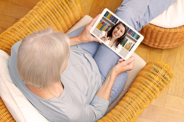 E-learning concept: senior woman with tablet computer watching an online english lesson.