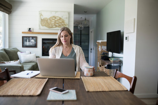 Woman working from home, using laptop in dining room