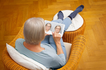 Shopping eyeglasses online concept: senior woman choosing her new glasses at home in her living...