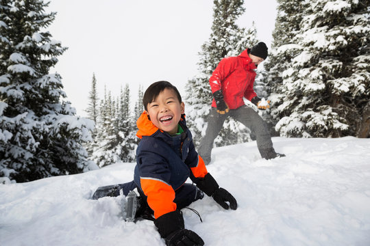 Happy, carefree son enjoying snowball fight with father
