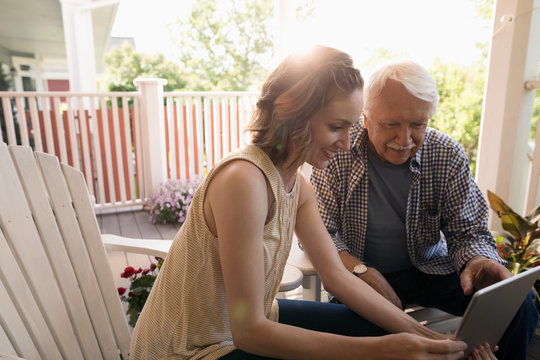 Daughter and senior father using digital tablet on porch