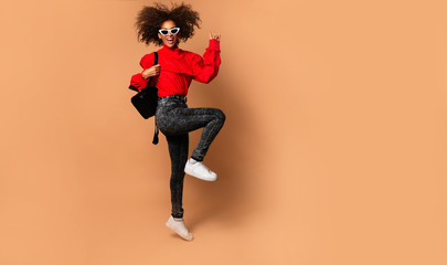 Good-humoured african lady jumping with smile.Indoor photo of emotional birthday girl dancing.Crazy party mood.Success.