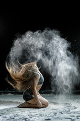 Obraz na płótnie Canvas Beautiful girl model on a black background throws flour