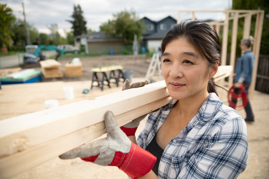 Woman carrying wood planks at construction site