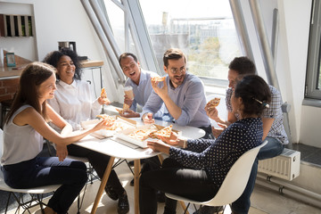 Happy diverse colleagues eating pizza during office work break