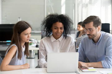 Diverse interns working on laptop during office training