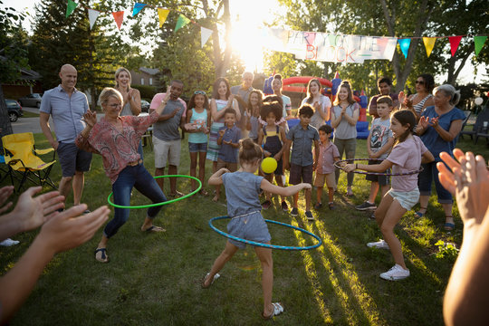 Neighbors spinning in plastic hoops at summer neighborhood block party in park