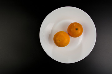 Two mandarines lie on a plate