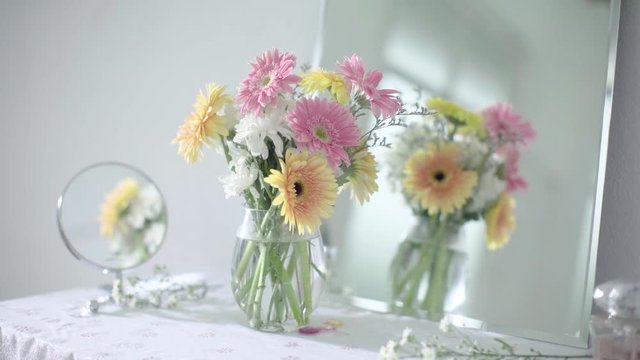 Shift Focus From Mirror A Bouquet of Bloom Pink and Yellow Daisy Flower in Glass Vase on Dressing Table 