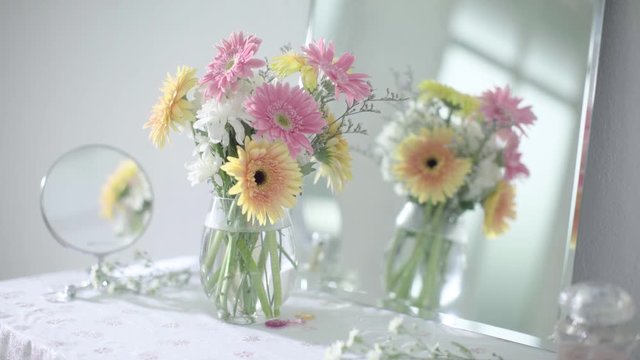 Camera Dolly Side A Bouquet of Bloom Pink and Yellow Daisy Flower in Glass Vase on Dressing Table 